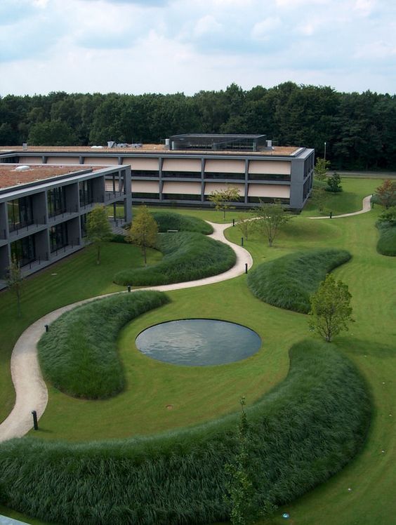 an aerial view of a large building with a pond in the center and grass around it