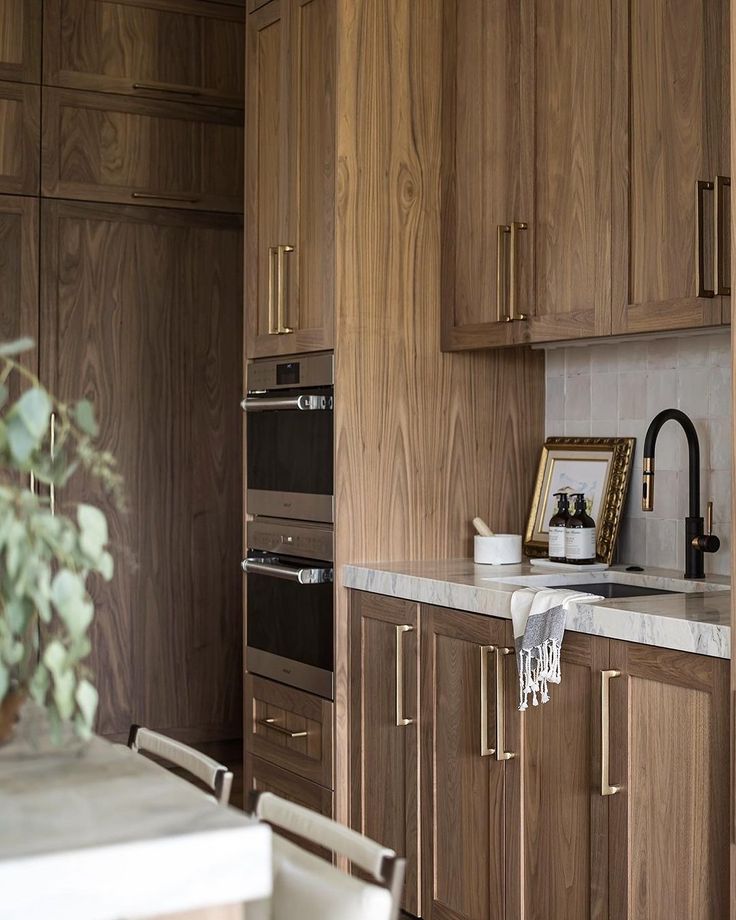 a kitchen with wooden cabinets and marble counter tops, along with a potted plant