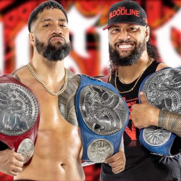 two men standing next to each other holding wrestling belts