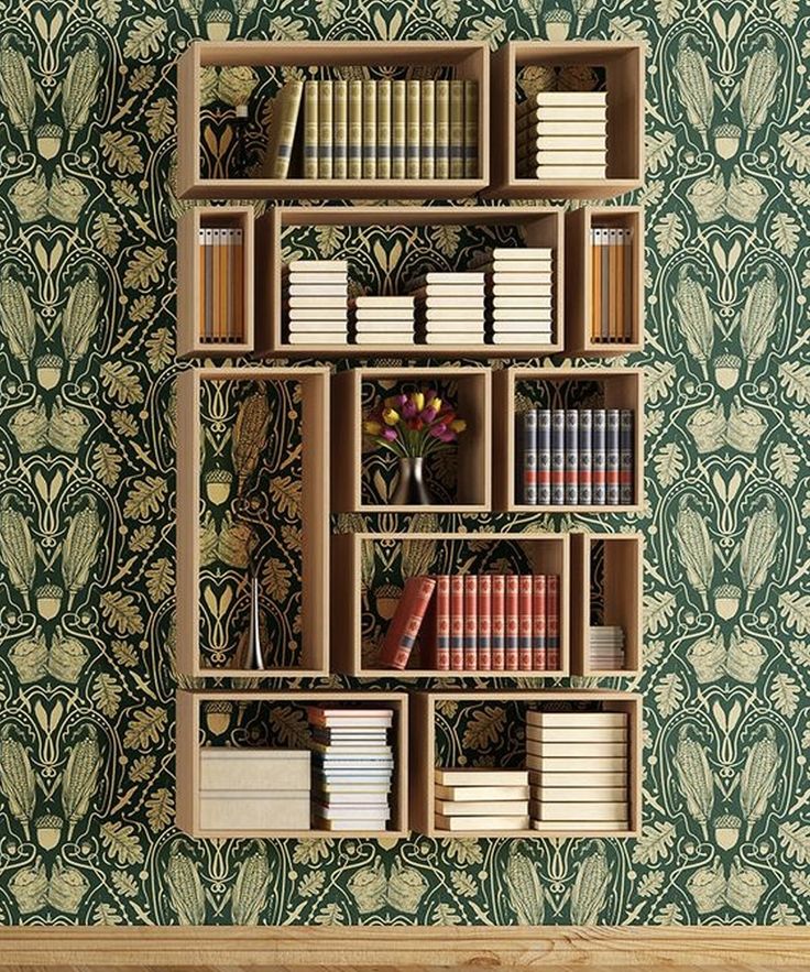 a bookshelf filled with lots of books in front of a wallpapered wall