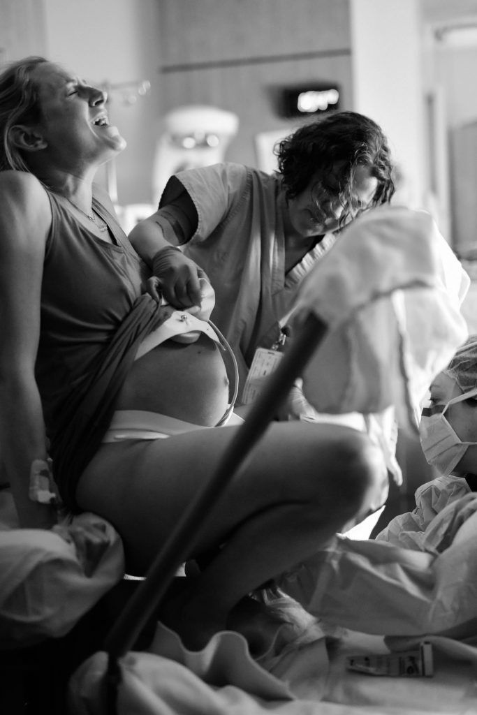 two women in hospital gowns are looking at something on the bed while another woman stands near her