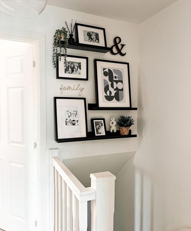 some black and white pictures hanging on the wall next to a stair case in a home