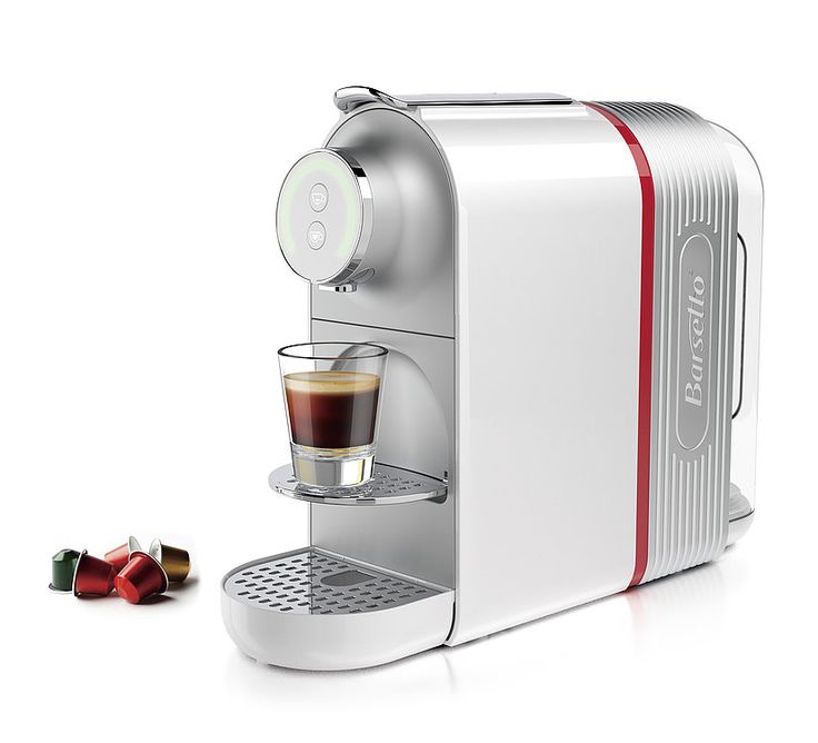 an espresso machine with a cup of coffee next to it on a white surface