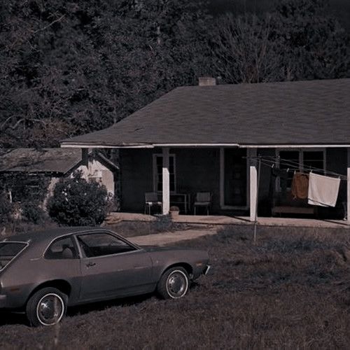 an old car parked in front of a house with clothes hanging out to dry on the line