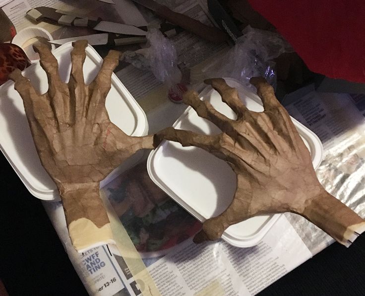 two hands that are made out of paper on top of a table with plates and utensils