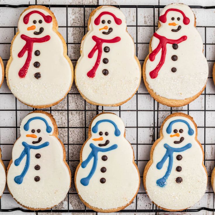 frosted cookies decorated like snowmen on a cooling rack