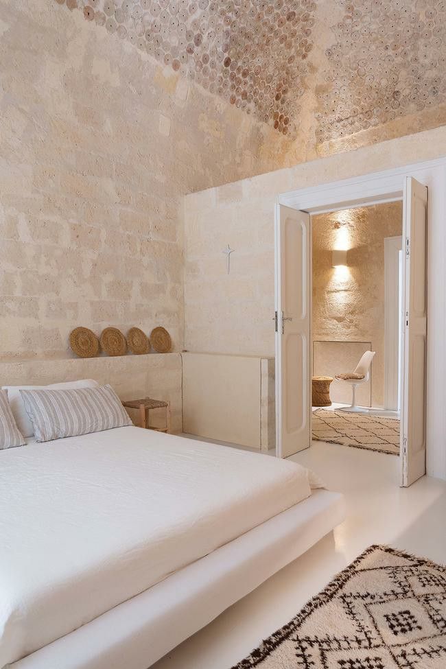 a white bed sitting inside of a bedroom on top of a rug next to a doorway