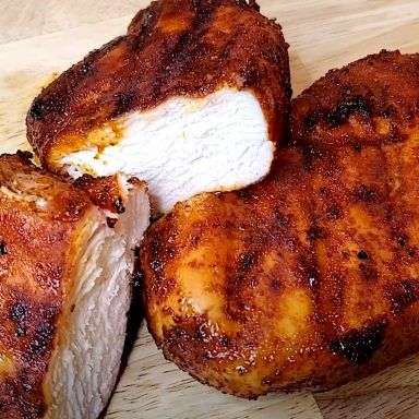 three pieces of chicken sitting on top of a wooden cutting board