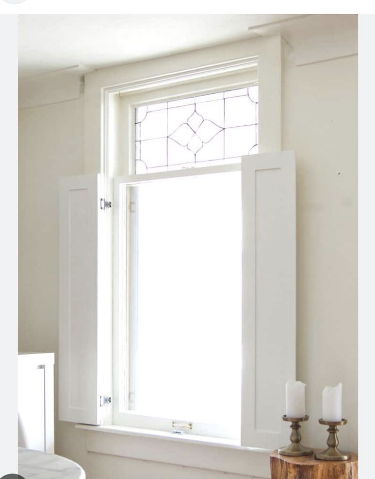 a bathroom window with candles on the counter