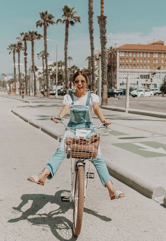 a woman is riding her bike down the street with palm trees in the back ground