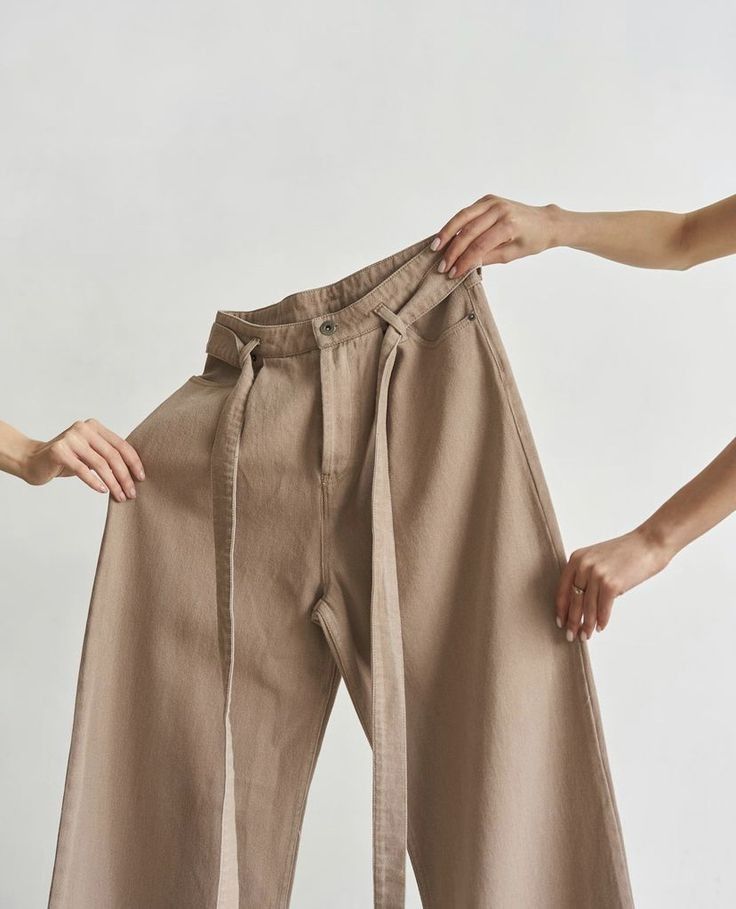 two women are holding their pants with one hand and the other is pulling them up