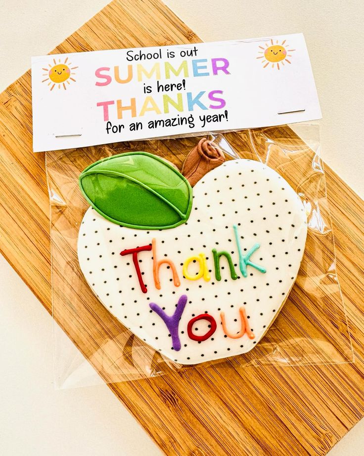 a thank you cookie with a green leaf on it sitting on top of a cutting board