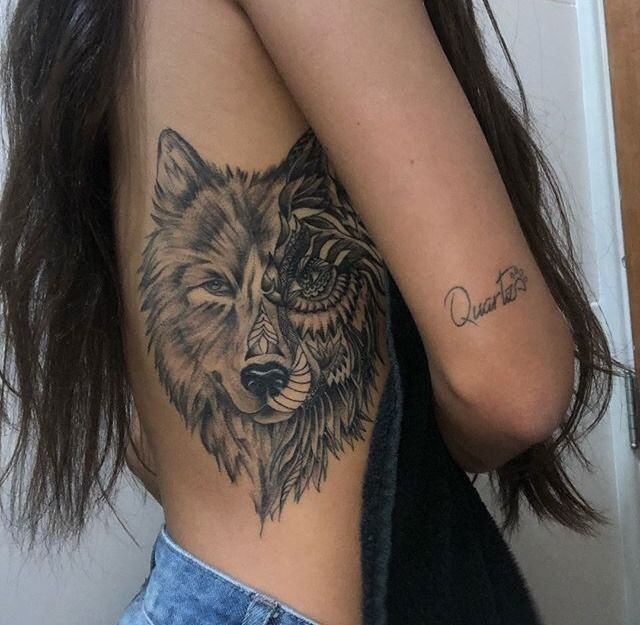 a woman with a wolf tattoo on her arm and shoulder is looking at the camera