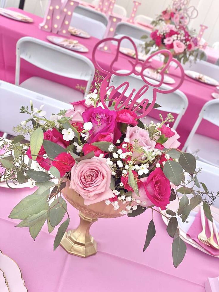 a vase filled with pink flowers sitting on top of a table covered in plates and napkins