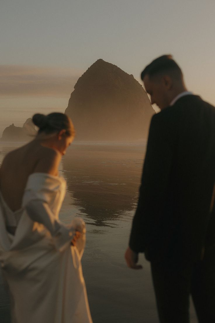 a man and woman standing next to each other in front of a body of water