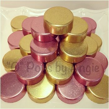 gold and pink round candy tins stacked on top of each other in a pile