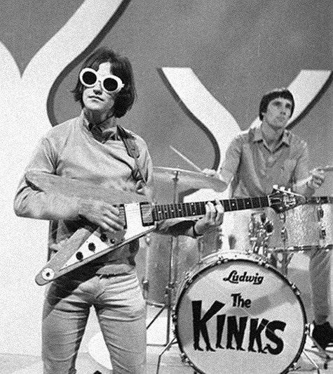 the kinks performing on stage in front of an advertisement for their new album,