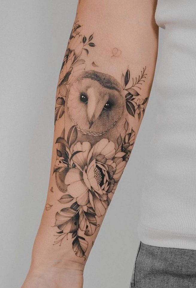 an owl and flowers tattoo on the arm