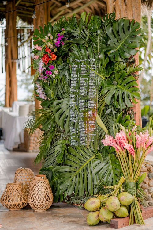 a table with flowers and greenery on it next to some other items in front of a wooden structure