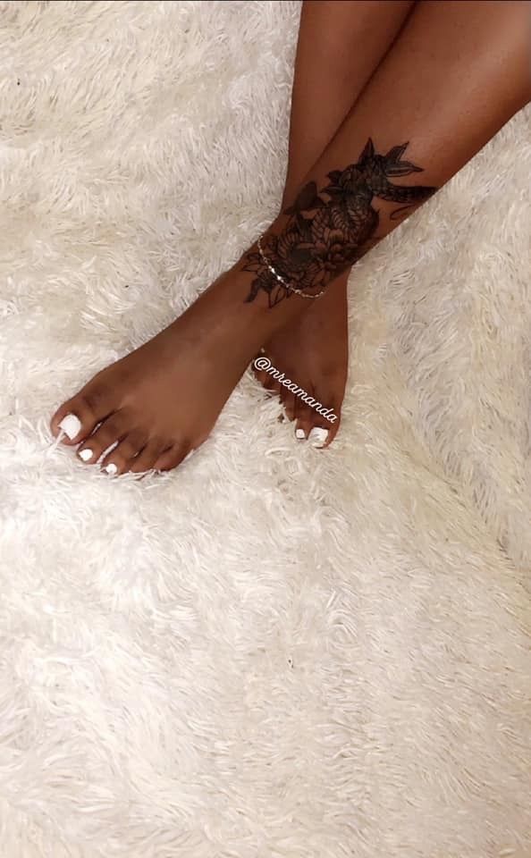 a woman's foot with tattoos on it sitting on a fluffy white rug in front of her