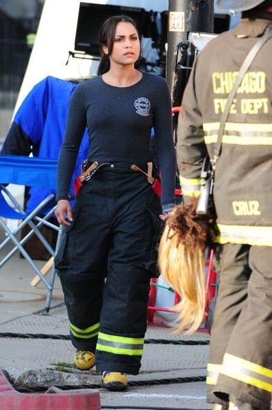 a woman in fire fighter gear walking down the street