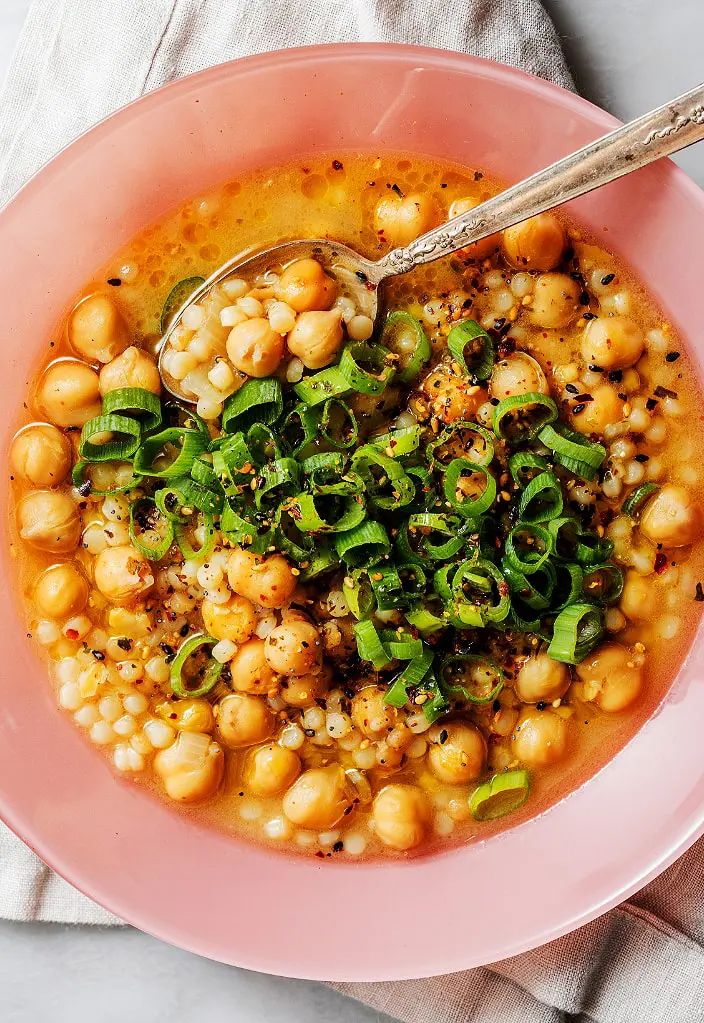 a pink bowl filled with chickpeas and spinach