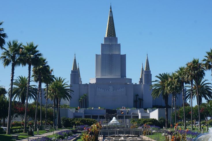 a large building with many spires and palm trees around it in front of a fountain