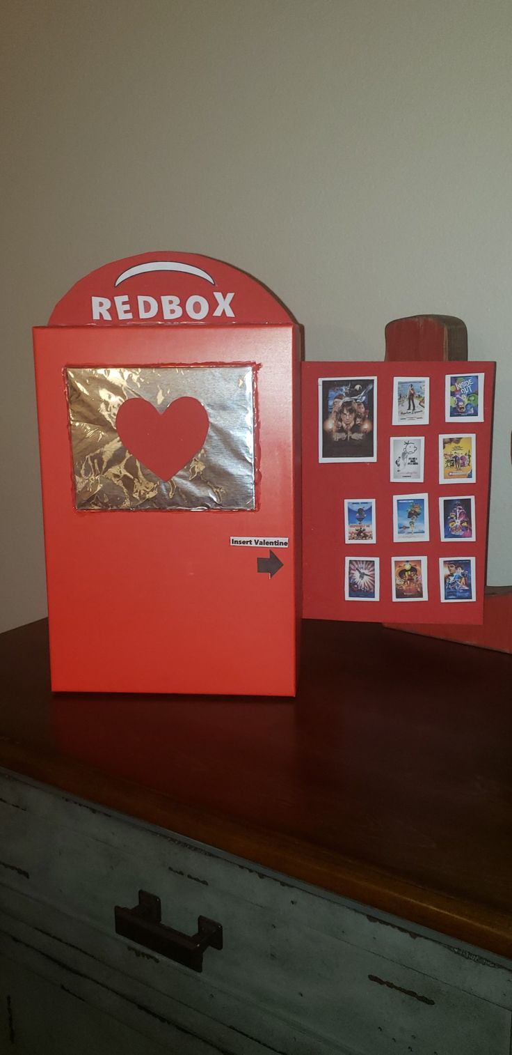 a red box sitting on top of a wooden table next to pictures and a cup