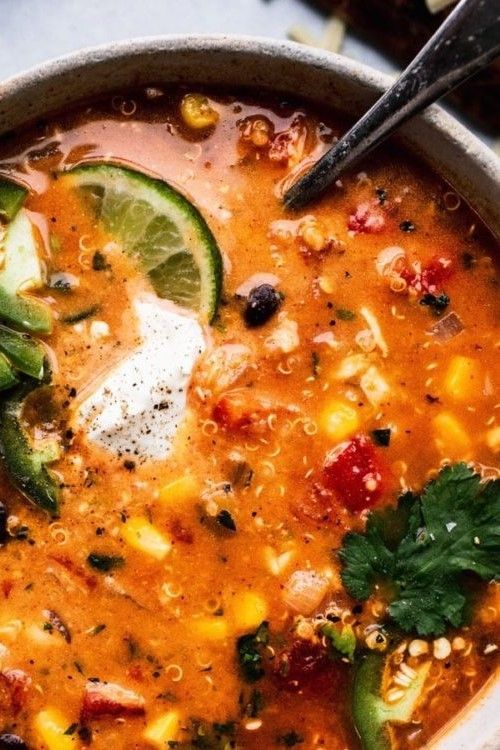 a bowl of mexican soup with tortilla chips and avocado on the side