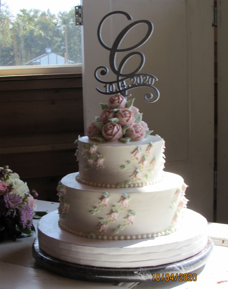 a three tiered wedding cake sitting on top of a table next to a window