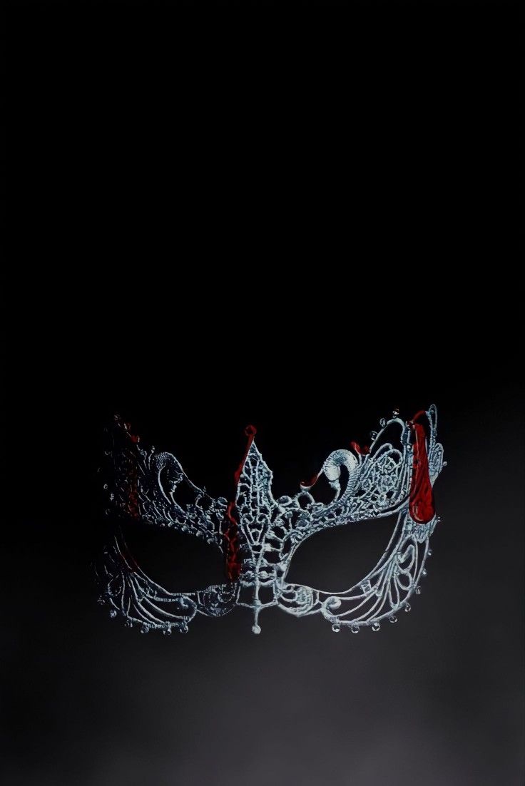 a white mask with red accents on it's face in the dark, against a black background