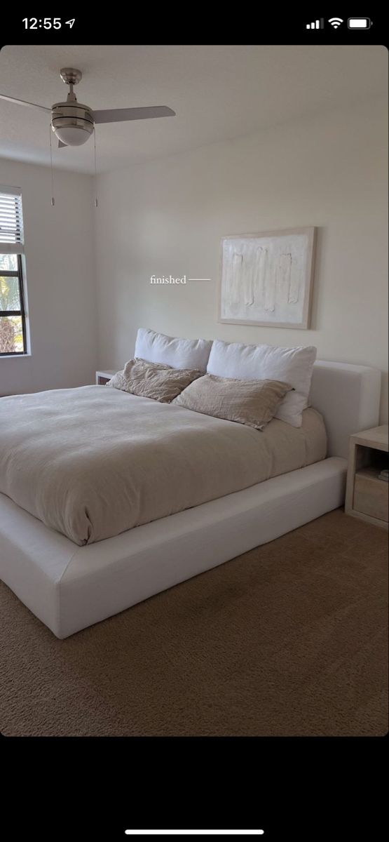 a large white bed sitting in a bedroom next to a window