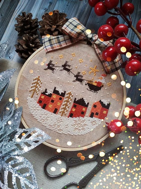 a cross stitch christmas ornament on a table next to scissors and other holiday decorations