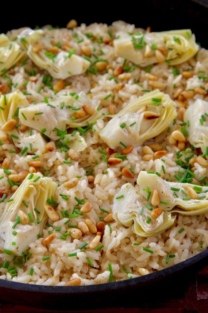 a skillet filled with rice, artichokes and nuts