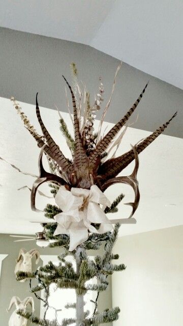 a deer head hanging from the ceiling next to a christmas tree decorated with white bows