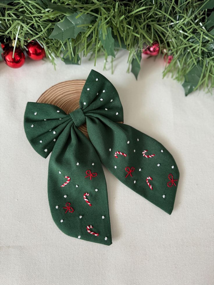 a green bow tie with candy canes on it sitting next to some christmas decorations