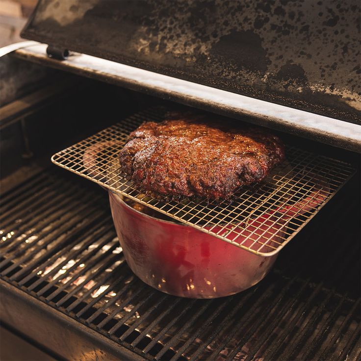 a steak cooking in an oven on top of a red pot