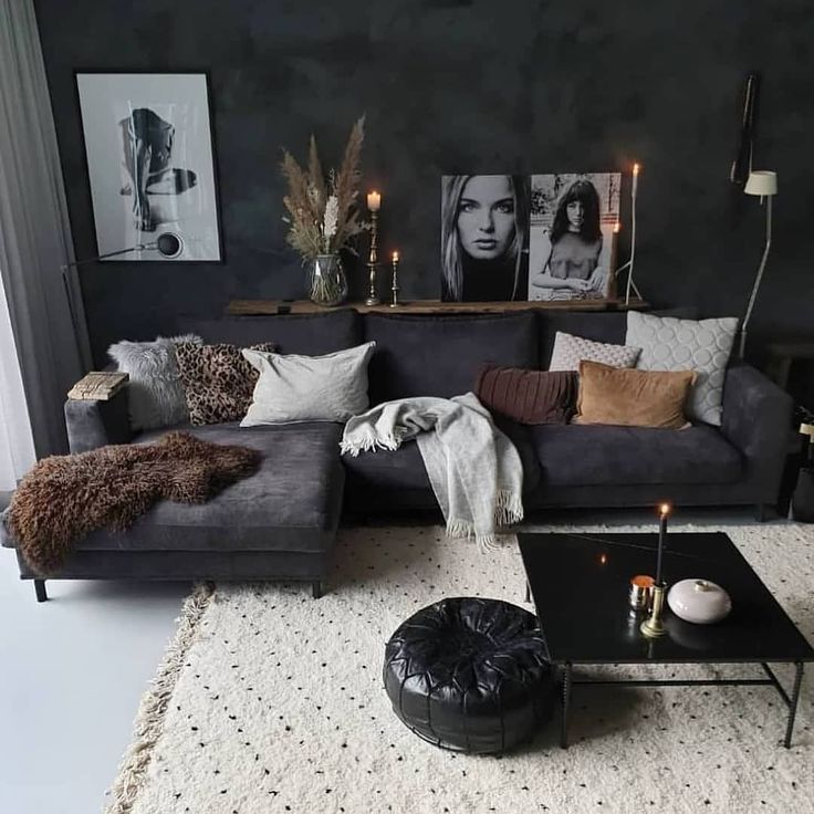 a living room filled with black furniture and lots of pillows on top of the couch