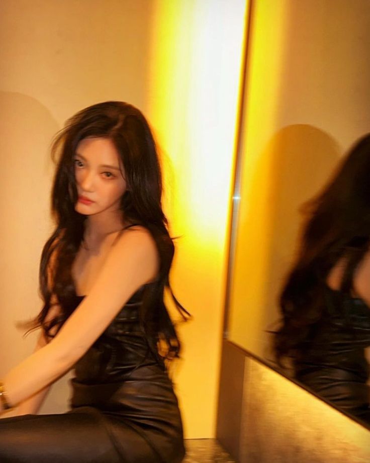 a woman sitting on top of a counter next to a mirror