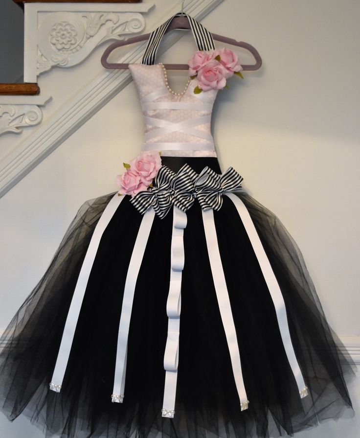 a black and white dress with pink flowers on the waist, hanging from a hanger