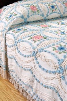 a bed with a blue and white quilt on it's coverlet next to a wooden headboard