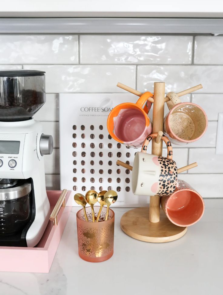 a kitchen counter with coffee maker, cups and utensils