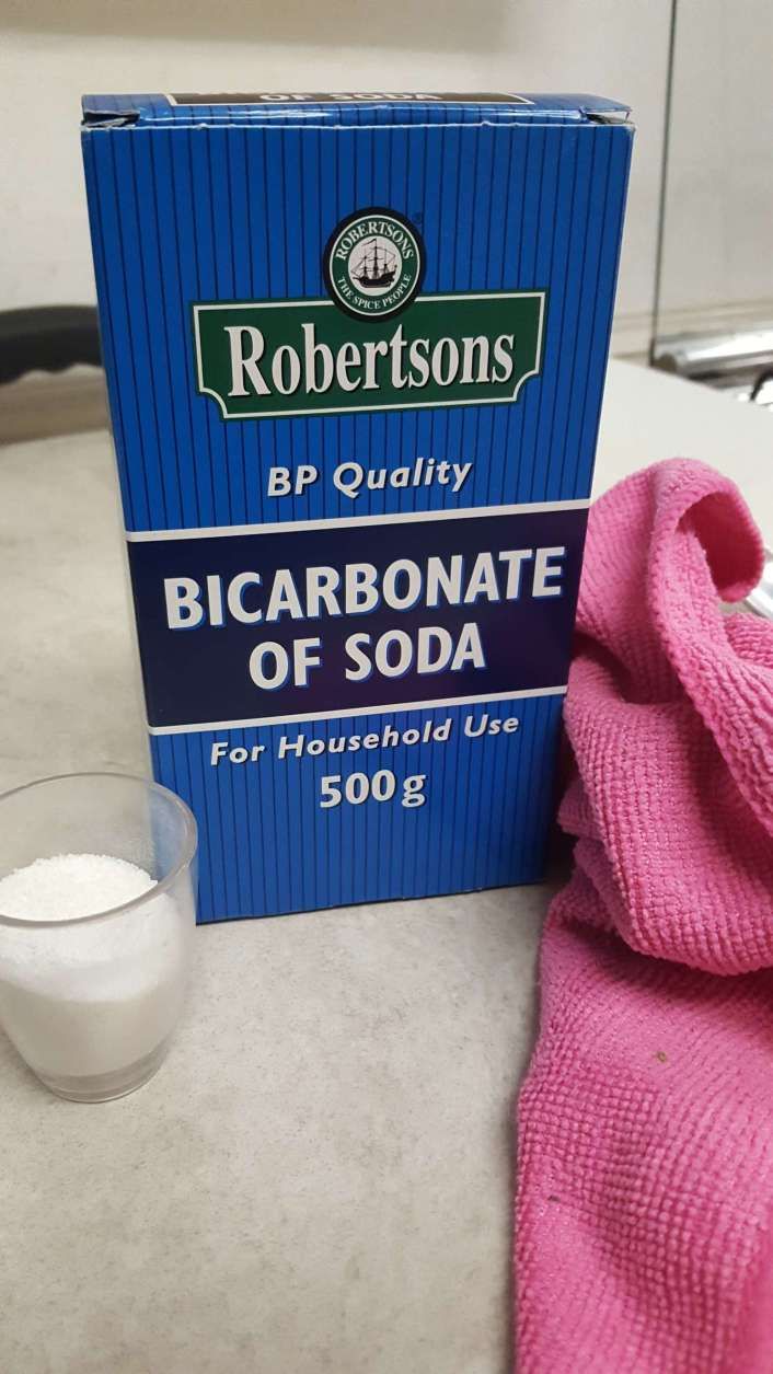 a bottle of alcohol next to a pink towel and a glass of water on a table