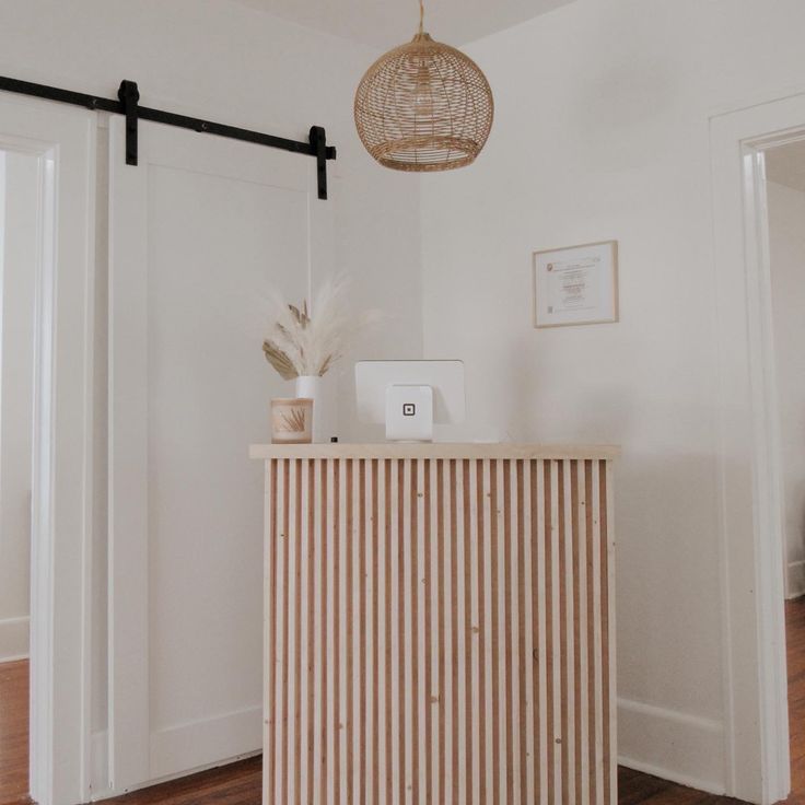 a white room with a wooden cabinet and light fixture hanging from it's ceiling