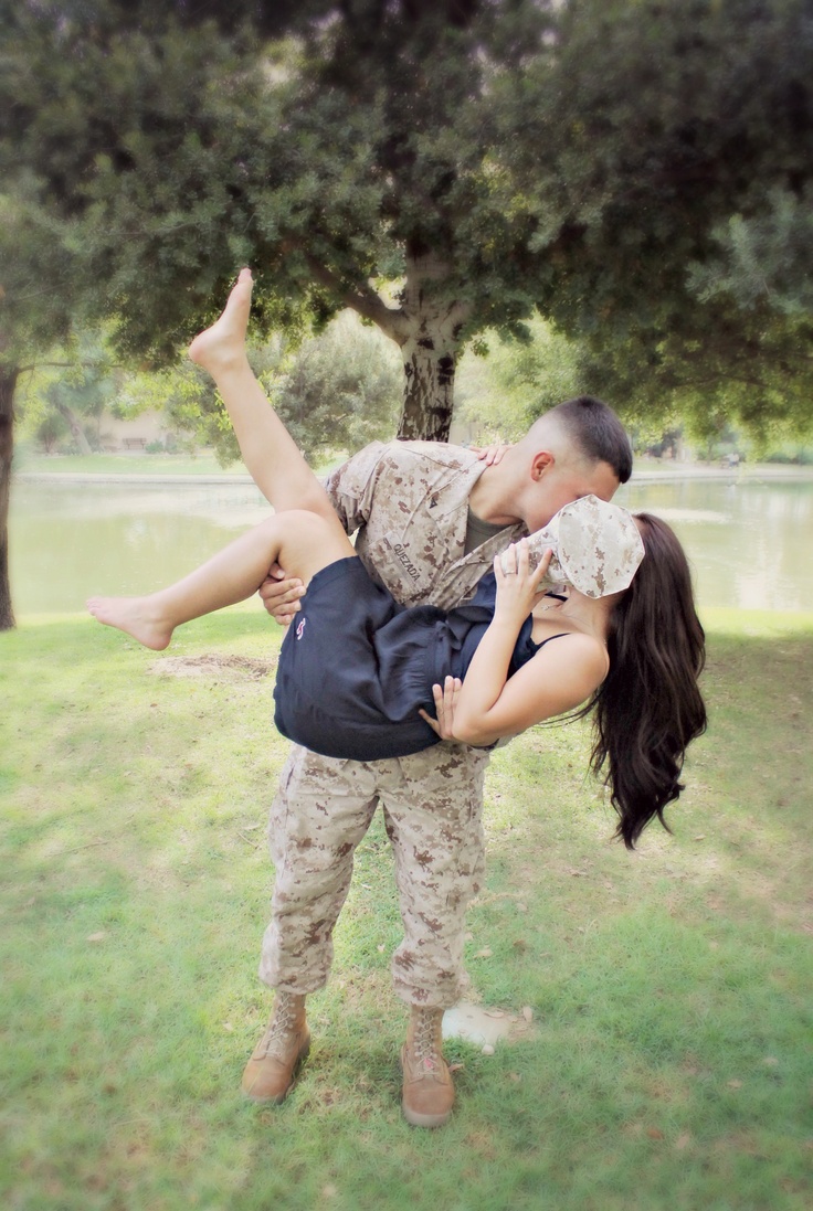 a man and woman are kissing in the grass near a tree with their legs spread out