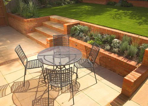 a patio with chairs and table in the middle of it, surrounded by brick walls