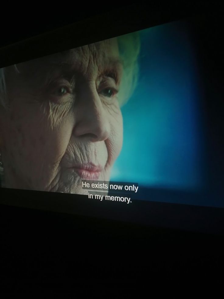 an old woman's face is projected on a television screen with the caption, life ends now only in my memory