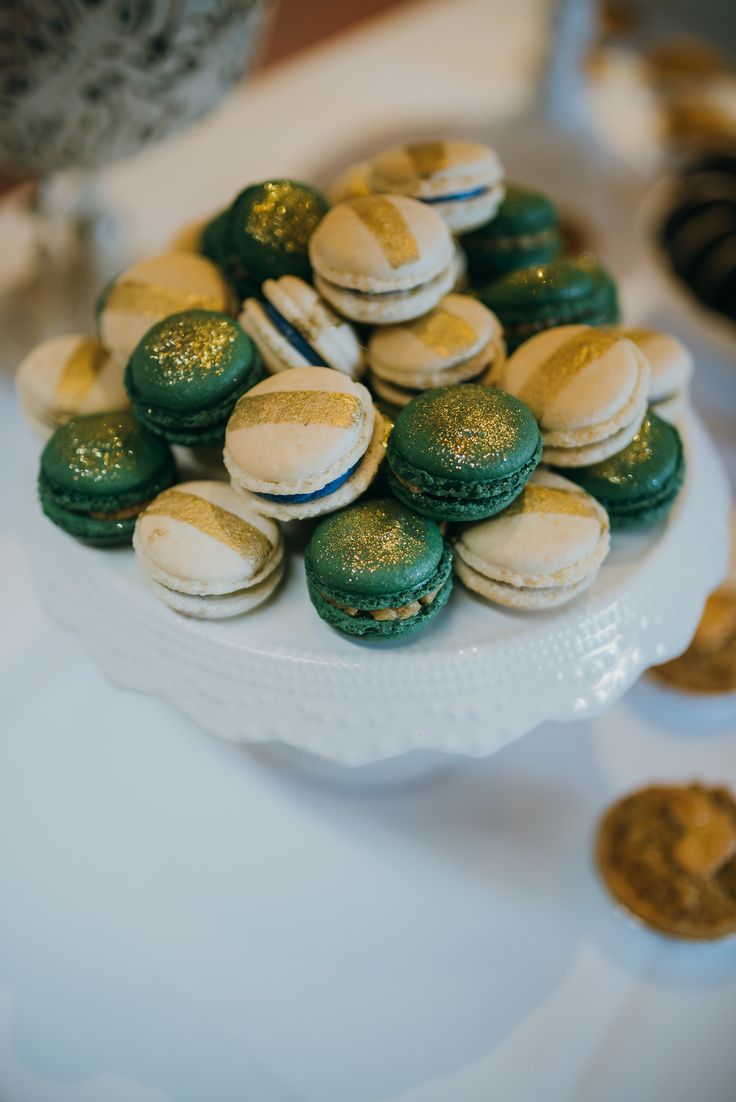 green and white macaroons on a plate with gold flecks around them