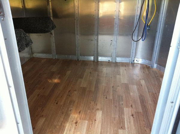 the inside of a horse trailer with wood flooring and metal partitions on both sides