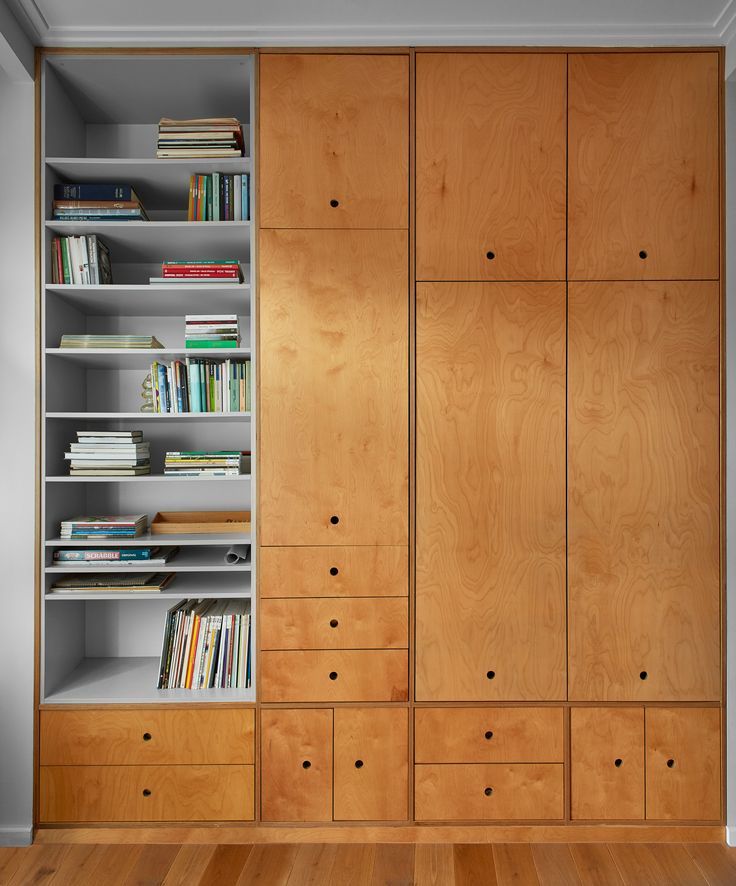 an empty room with wooden cabinets and bookshelves on the wall, along with hard wood flooring